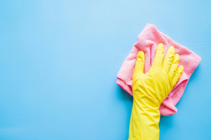 Does an AC Kill Mold? Employee hand in rubber protective glove with microfiber rag wiping blue table, wall or floor surface in room, bathroom, kitchen. Early spring or regular cleanup. Commercial cleaning company concept.