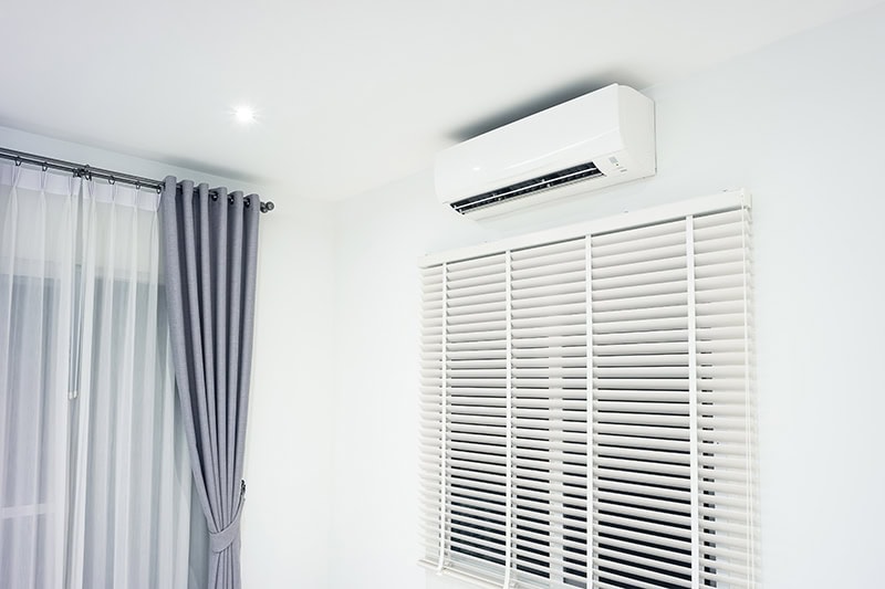 A ductless unit on the wall next to blue curtains